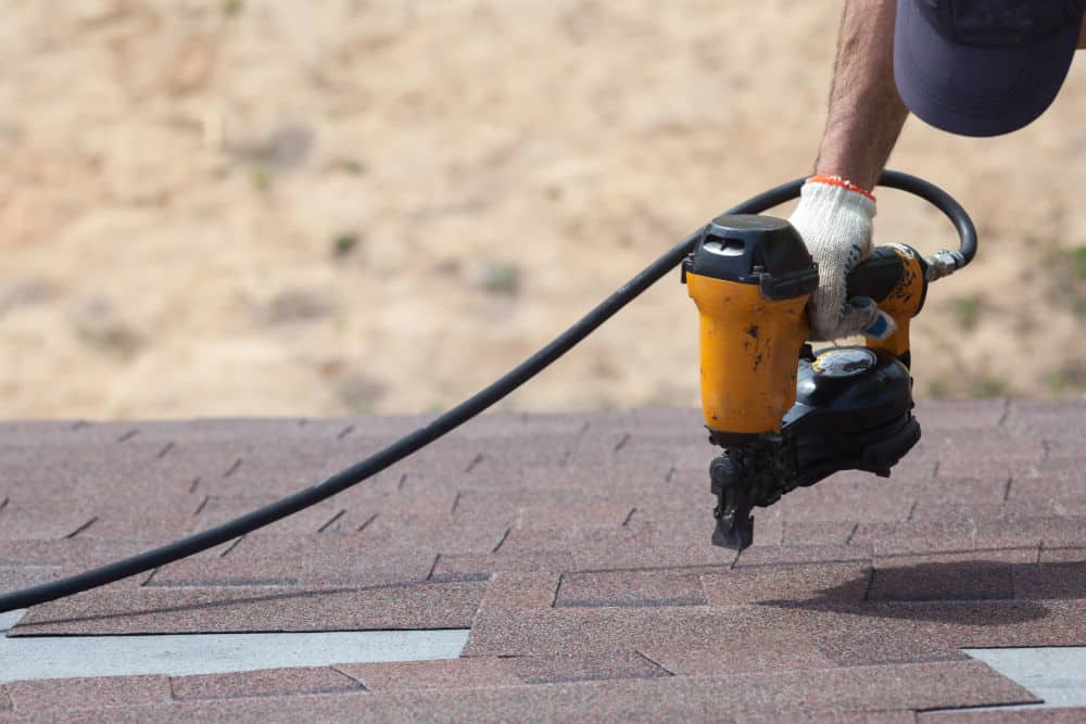 A commercial roofing contractor replaces shingles on a building.